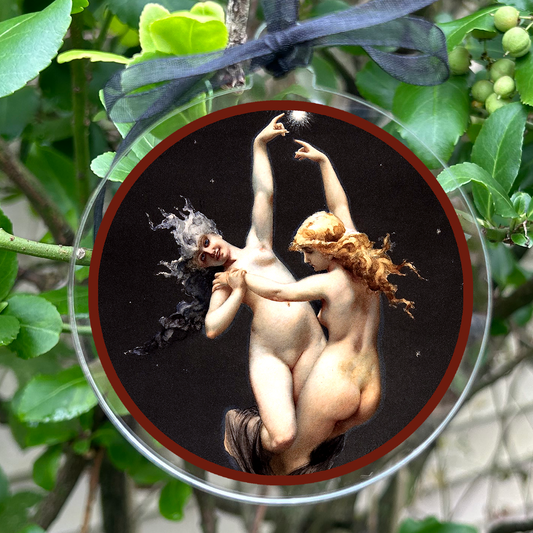 A round hanging ornament with a black ribbon loop, featuring a classical painting of two dancing figures on a dark background, displayed among green leaves and branches.
