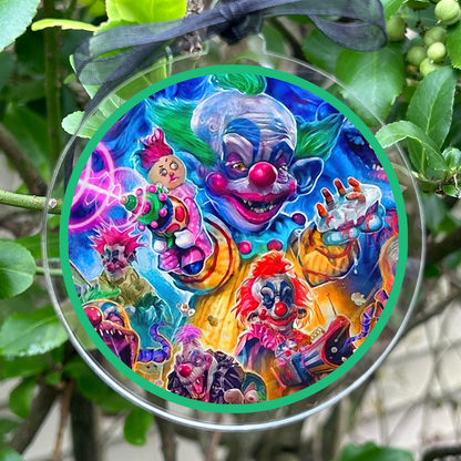 A round clear acrylic hanging ornament with a black ribbon, featuring a highly colorful illustration of various cartoon clowns, photographed hanging outdoors among green leaves and branches.